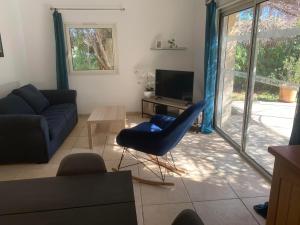 sala de estar con sofá azul y TV en Les jonquiers, gîte indépendant cosy avec jardin, en Aubagne