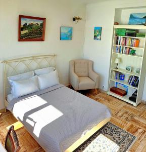 sypialnia z łóżkiem, krzesłem i półką na książki w obiekcie Sea view studio terrasse Cap Martin/Monaco w mieście Roquebrune-Cap-Martin