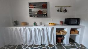 een keuken met een aanrecht met spoelbak en magnetron bij Styfilia Beachfront Apartment - Ground Floor in Sifnos +5 foto's