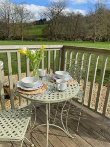 einen Tisch mit Teller und Schalen und eine Vase Blumen auf dem Balkon in der Unterkunft Kingfisher in Chirk