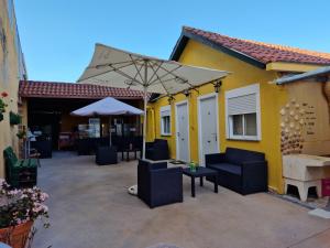 a patio with chairs and an umbrella and a building at Pensión O Muiño in O Pedrouzo