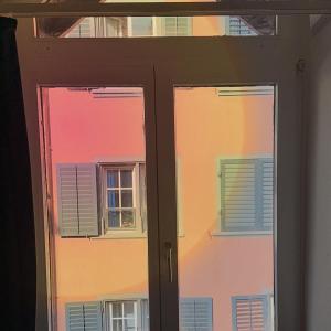 een glazen schuifdeur met uitzicht op twee ramen bij City Center Apartment in Zürich