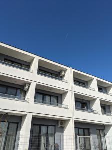 a white apartment building with a blue sky in the background at Alina's Deluxe Apartment and free private parking in Dumbrăviţa