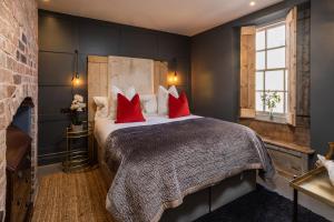 a bedroom with a large bed with red pillows at The Walled Garden at Cheshire Boutique Bathhouse in Nantwich