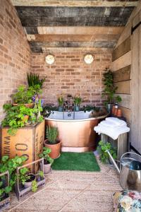 uma casa de banho com uma banheira com plantas em The Walled Garden at Cheshire Boutique Bathhouse em Nantwich