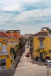 uma rua da cidade com casas amarelas e um carro vermelho em 4CB-1 CASA COLONIAL DE 4 HABITACIONES EN EL CENTRO HISTORICO DE CARTAGENA em Cartagena das Índias