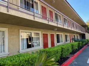 een gebouw met rode deuren en struiken ervoor bij Rivera Inn & Suites Motel in Pico Rivera