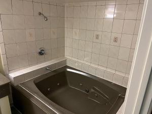 a bath tub in a bathroom with a tiled wall at Rivera Inn & Suites Motel in Pico Rivera