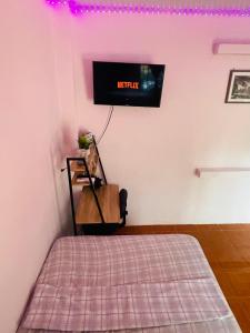 1 dormitorio con 1 cama y TV en la pared en Hostal Mónaco, en San Miguel