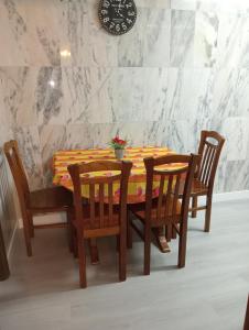 uma mesa de jantar com quatro cadeiras e um relógio na parede em Apartamento Alvares Cabral em Vila Nova de Gaia