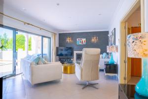 een woonkamer met twee stoelen en een televisie bij Ocean View Villa in Boliqueime