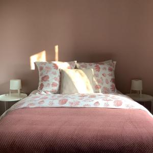 1 dormitorio con 1 cama con sábanas y almohadas rosas en Le jardin Chamberlin, Chambres d'hôtes en Savigny-sur-Orge