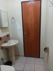 a bathroom with a wooden door and a sink at Brisa da Serra Hotel Pousada Pirenopolis in Pirenópolis