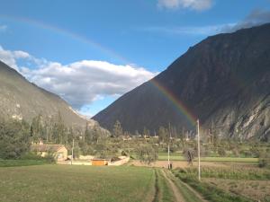 a rainbow over a field with a mountain at Casafranca in Ollantaytambo