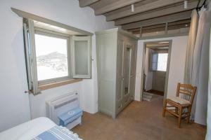 een slaapkamer met een bed, een raam en een stoel bij Patmos Traditional House Chora near the Monastery in Patmos