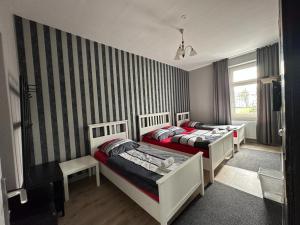 a bedroom with two beds and a striped wall at Adam's Hostel - Self Check-In & Only Private Rooms in Düsseldorf +9 photos