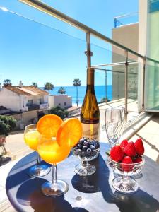 a table with wine glasses and fruit on a balcony at Beach Condo with Atlantic Ocean View by BeCherish in Olhos de Água