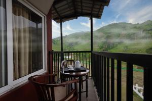 a balcony with two chairs and a table with a view at Misty Gate in Vythiri