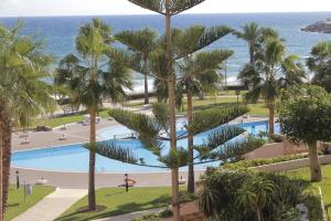 mit Blick auf einen Pool mit Palmen und das Meer in der Unterkunft Appartement Marina Beach - Belle Vue in Mʼdik