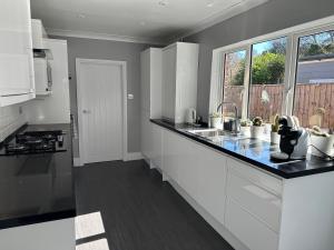a kitchen with white cabinets and a black counter top at Remarkable 3-Bed House in East Cowes in East Cowes