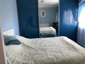 Remarkable 3-Bed House in East Cowes في إيست كاوز: غرفة نوم زرقاء مع سرير ومرآة