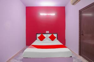 a bed in a room with a red wall at Primrose Hotel's Near Noida Sector Metro Station in Noida