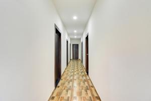 a long corridor with white walls and wooden floors at Collection O Pratik Inn in Chinhat