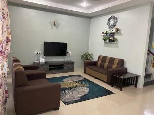 - un salon avec deux chaises et une télévision à écran plat dans l'établissement Makmur homestay, à Taiping