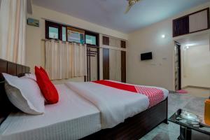 1 dormitorio con 1 cama grande con almohadas rojas en Super OYO Flagship Rajbanshi Nagar en Patna
