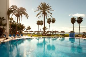 a large swimming pool with palm trees and the ocean at Ona Marinas de Nerja Spa Resort in Nerja