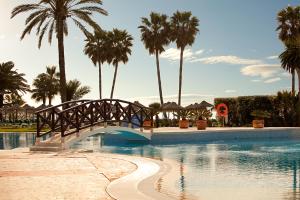 a bridge over a swimming pool with palm trees at Ona Marinas de Nerja Spa Resort in Nerja