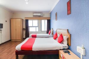 a bedroom with two beds with red and white pillows at OYO Luxury Villas Near Begumpet Airport in Ameerpet