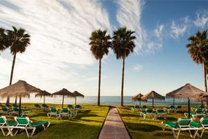 a path leading to the beach with chairs and palm trees at Ona Marinas de Nerja Spa Resort in Nerja