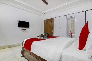 a white bedroom with a large bed and a television at Alpine Glow Crest in Secunderabad