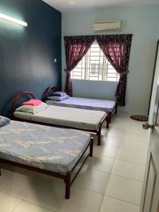a room with three beds and a window at Makmur homestay in Taiping