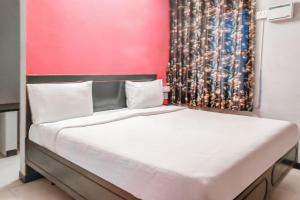 a bed in a room with a red wall at OYO Hotel Kota Lodge in Coimbatore
