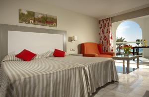 a hotel room with a large bed with red pillows at Marinas de Nerja Beach & Spa in Nerja