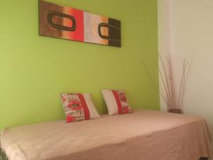 ein grünes Zimmer mit einem Bett mit zwei Kissen darauf in der Unterkunft Apart Pm Albatros in Necochea