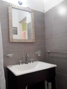 ein Badezimmer mit einem weißen Waschbecken und einem Spiegel in der Unterkunft Apart Pm Albatros in Necochea