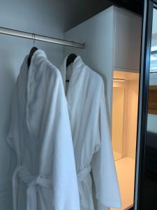 a closet with white robes hanging on a rack at Studio Unit with Spa Bath in Christchurch