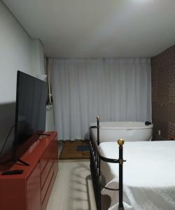 1 dormitorio con 1 cama, TV y bañera en Loft Espaço Vila da Serra en Nova Lima