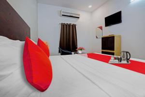 um quarto com uma cama grande e almofadas vermelhas em Sai Krishna Residency em Vijayawada