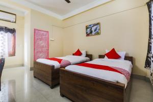 um quarto com 2 camas e almofadas vermelhas em OYO Alohi Ghar em Bhutiāgāon