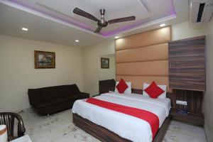 een slaapkamer met een groot bed en een bank bij Super OYO Hotel Samrat in Gurgaon