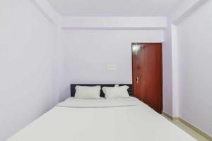 a white bed in a white room with a wooden door at Flagship Hotel Paradise Inn in Patna