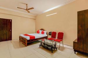 a bedroom with a bed and two red chairs at Sahasra Residency 43619 Near Nexus Hyderabad in Hyderabad