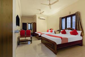 two beds in a room with two red chairs at Sahasra Residency 43619 Near Nexus Hyderabad in Hyderabad