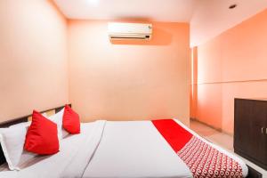 a bedroom with a bed with red pillows at Hotel Priyal in Chās