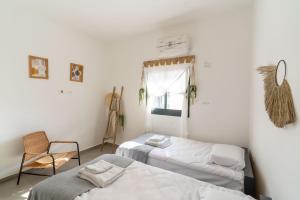 a room with two beds and a chair and a window at HaKerem new luxury 3 rooms apartments and 2 rooms penthaus in Tel Aviv