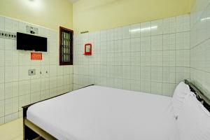 a room with a bed and a tv on the wall at OYO 86379 Dream Palace Guest House Near Marina Beach in Chennai